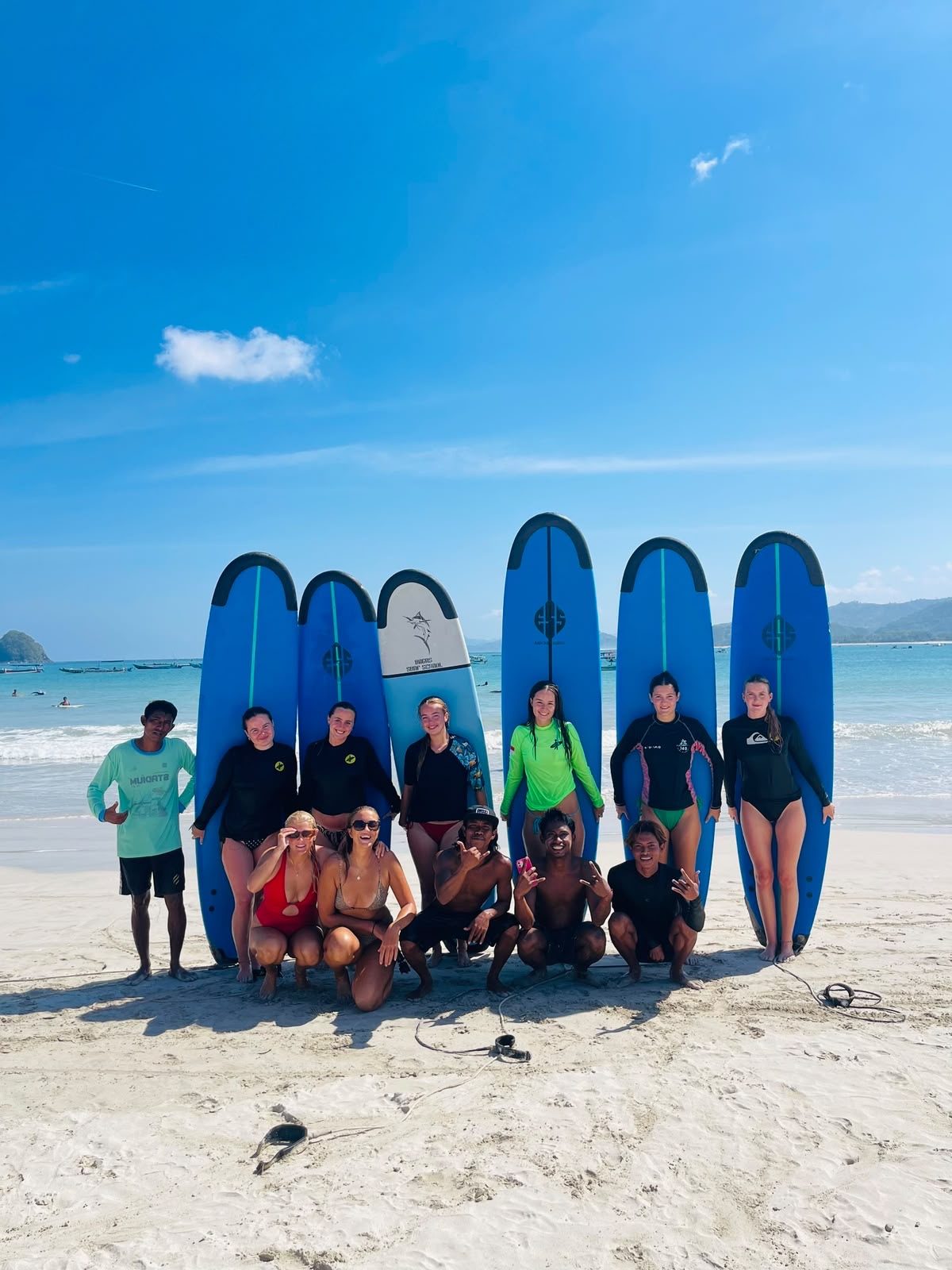 Wawan and a group of students with surfboards on the beach in Lombok