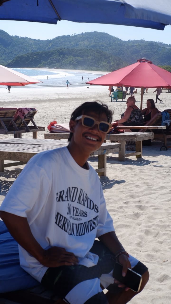 Instructor smiling on the beach with the surf break behind him