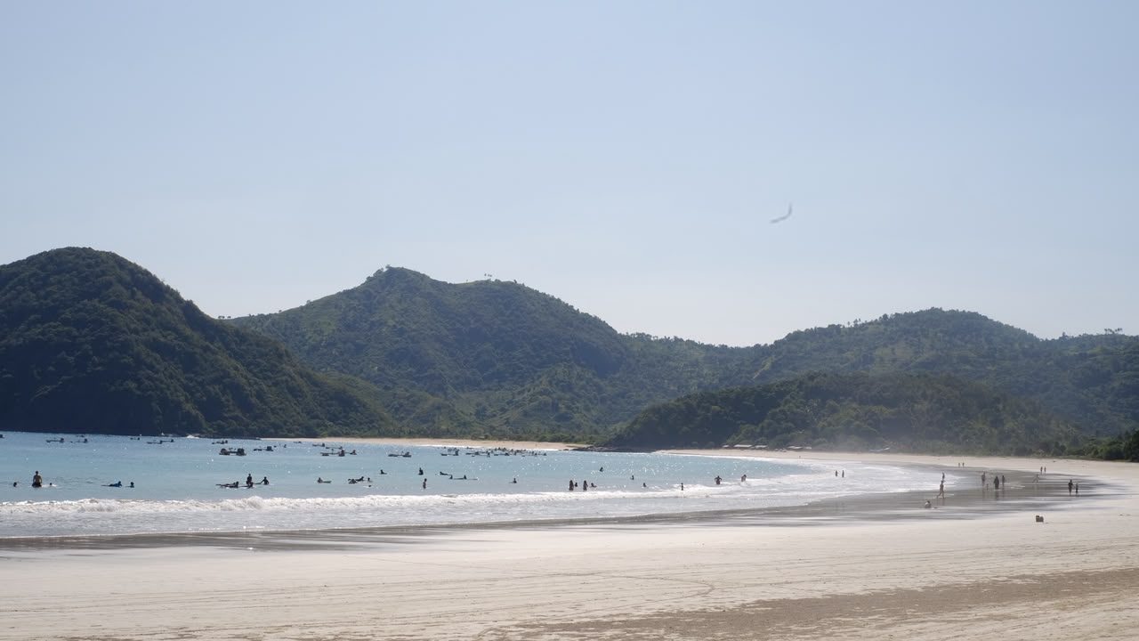 Students surfing and swimming in the lineup at Selong Belanak