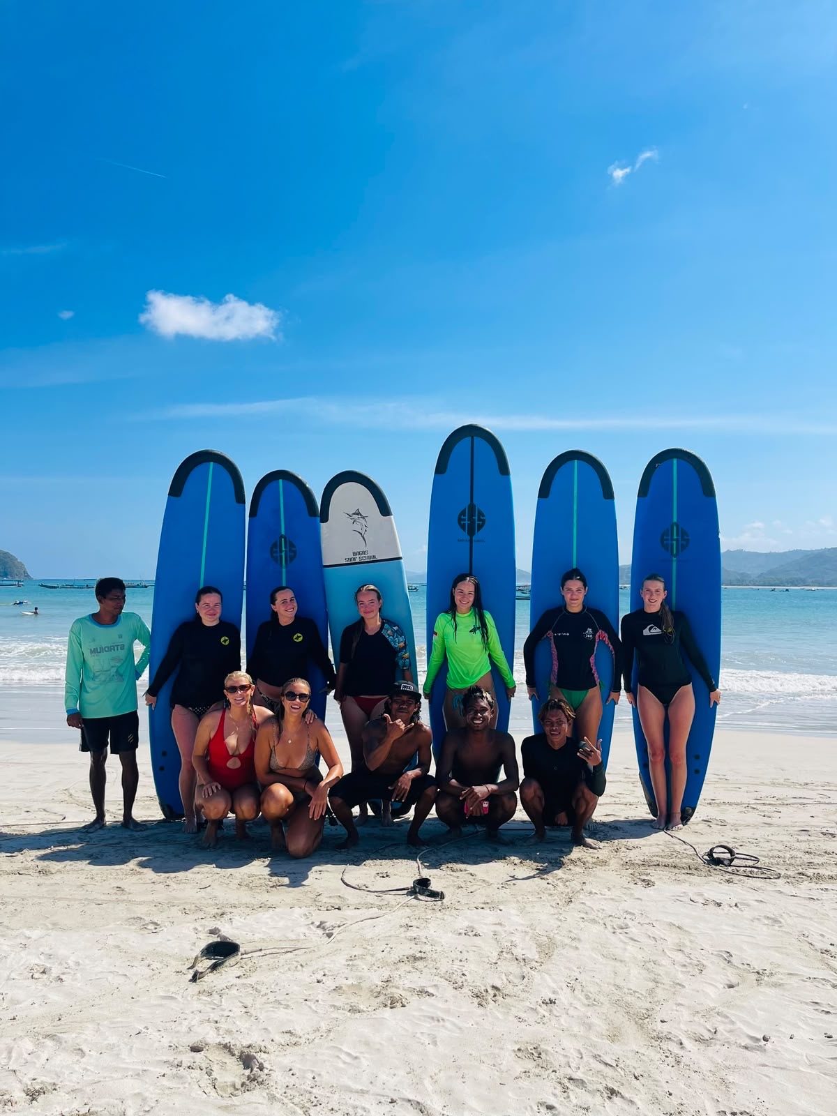 Wawan and a group of students posing with surfboards on the beach